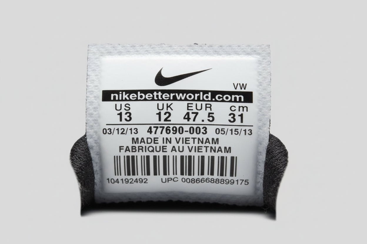 Hand holding a small toy with a Nike label on a wooden surface