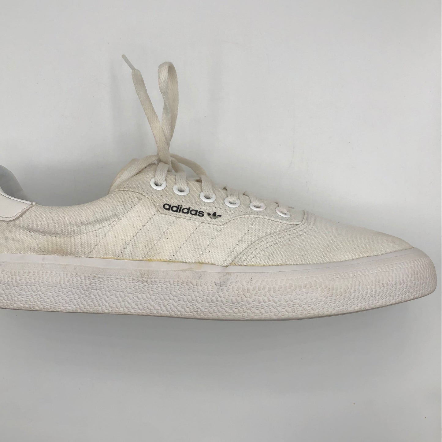 White Adidas sneaker on a light gray background