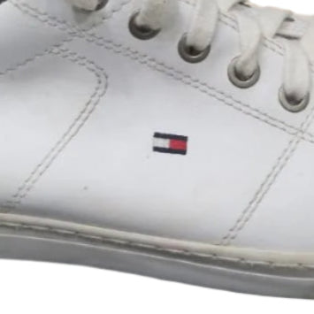 White sneaker with a brand logo on a black surface